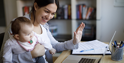 image of a mother holding a baby while videoconferencing on a laptop